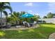 Landscaped backyard featuring a circular patio with seating and a turquoise umbrella at 14702 Dartmoor Ln, Tampa, FL 33624
