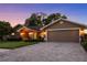 Inviting home exterior featuring a manicured lawn, mature trees, and a wide driveway leading to the garage at 14702 Dartmoor Ln, Tampa, FL 33624
