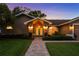 Beautiful home exterior at dusk, showcasing the front entrance, manicured lawn, and inviting lighting at 14702 Dartmoor Ln, Tampa, FL 33624