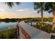 Scenic boardwalk with wooden railing overlooking a tranquil lake surrounded by palm trees and lush greenery at sunset at 14702 Dartmoor Ln, Tampa, FL 33624