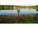 Scenic lake view with a fountain and warning sign about alligators in reclaimed water at 14702 Dartmoor Ln, Tampa, FL 33624