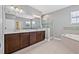 Bathroom featuring double vanity, a soaking tub, glass shower, and neutral tile at 14718 Rocky Brook Dr, Tampa, FL 33625