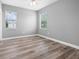 Bedroom with light wood floors, gray walls, two windows, and bright natural light at 14718 Rocky Brook Dr, Tampa, FL 33625