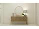 Elegant entryway with woven console table, round mirror, decorative lamp, and tasteful decor at 18468 Serene Lake Loop, Lutz, FL 33548