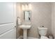 Chic powder room with a pedestal sink, decorative mirror, and patterned wallpaper at 231 2Nd S St # 201, Safety Harbor, FL 34695