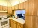 Kitchen featuring light wood cabinets and white appliances, with an open view to the living area at 2643 Pine Ridge S Way # A1, Palm Harbor, FL 34684