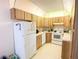 Clean kitchen featuring white appliances, light wood cabinetry, and functional layout at 2643 Pine Ridge S Way # A1, Palm Harbor, FL 34684