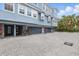 Exterior view of a light blue three-story townhome with multiple garages and a brick driveway at 3111 W De Leon St # 8, Tampa, FL 33609