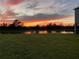 Scenic backyard view overlooking a tranquil lake, capturing a vivid sunset reflecting on the water at 33030 Major Oak Dr, Wesley Chapel, FL 33545