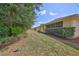 Spacious backyard with a screened lanai, lush lawn and side view of the yellow home at 3315 Granite Ridge Loop, Land O Lakes, FL 34638