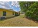 View of the grassy backyard with a lush green tree and the side of the yellow home at 3315 Granite Ridge Loop, Land O Lakes, FL 34638