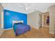 Bright bedroom featuring a bold blue accent wall, ceiling fan, and hardwood floors at 3414 Rankin Dr, New Port Richey, FL 34655