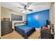 A cozy bedroom with a blue accent wall, ceiling fan, desk, and closet space at 3414 Rankin Dr, New Port Richey, FL 34655