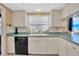 Well-lit kitchen with white cabinets, stainless appliances, and a window overlooking the outdoors at 3414 Rankin Dr, New Port Richey, FL 34655