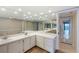 Well-lit bathroom featuring dual sinks, mirrored wall, tile flooring, and access to balcony views at 433 Mariner Dr # 433, Tarpon Springs, FL 34689