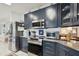 The kitchen features stainless steel appliances, granite countertops, and blue cabinetry at 5646 Cheyenne St, Zephyrhills, FL 33542