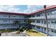 Three story exterior of condo with red roof, multiple balconies, tropical landscaping and dedicated parking at 5660 80Th N St # C101, St Petersburg, FL 33709