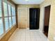 Bright living space featuring light beige wall coverings, tile floor, door, windows, and a dark cabinet at 5660 80Th N St # C101, St Petersburg, FL 33709