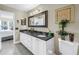 Double vanity bathroom with white cabinets, black countertops, framed mirror, and decorative accents at 6011 Bahia Del Mar Blvd # 158, St Petersburg, FL 33715