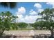 A serene view of the community tennis courts and landscape, framed by mature trees under a bright sky at 6150 Gulfport S Blvd # 306, Gulfport, FL 33707