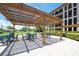 Outdoor patio area with pergola, tables, and chairs overlooking green space with golf course in the background at 6150 Gulfport S Blvd # 306, Gulfport, FL 33707
