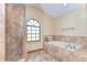 Bright bathroom with a walk-in shower, soaking tub, and a large arched window at 709 Sportsman Park Dr, Seffner, FL 33584