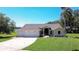 Inviting home featuring a three-car garage, manicured lawn, and beautiful landscaping with a view of the lake at 709 Sportsman Park Dr, Seffner, FL 33584