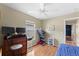 Bedroom featuring ceiling fan, window, and desk. Includes laminated wood flooring at 7235 Sharpsburg Blvd, New Port Richey, FL 34653