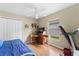 Bedroom featuring ceiling fan, window, treadmill, and desk. Includes laminated wood flooring at 7235 Sharpsburg Blvd, New Port Richey, FL 34653