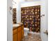 Cozy bathroom with a wood cabinet, toilet, and decorative shower curtain with bronze colored fixtures at 7285 Nightwalker Rd, Weeki Wachee, FL 34613