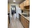 Open concept kitchen featuring stainless steel appliances, light wood cabinets, granite countertops, and wood-look flooring at 7951 58Th N Ave # 308, St Petersburg, FL 33709
