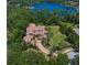 Stunning aerial view of a luxurious home with a red tile roof, surrounded by lush greenery and a beautiful lake at 1102 Merry Water Dr, Lutz, FL 33548