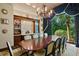 Formal dining room features a large table, brick accent wall, chandelier, and view to landscaped yard at 1102 Merry Water Dr, Lutz, FL 33548