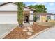 Home featuring an inviting front porch with stone details, mulch landscaping, and mature trees at 11318 Stoneybrook Path, Port Richey, FL 34668