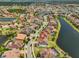 Expansive aerial view of a residential area featuring homes with tile roofs, lush greenery, and a winding waterway at 11909 Climbing Fern Ave, Riverview, FL 33579