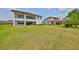 Spacious backyard with manicured lawn, patio, and a covered balcony with an exterior view of a well-maintained home at 11909 Climbing Fern Ave, Riverview, FL 33579