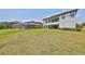 Expansive backyard featuring lush green grass, a patio, and exterior elevation with large windows and a screened in pool in the distance at 11909 Climbing Fern Ave, Riverview, FL 33579