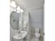 Bathroom featuring a pedestal sink, round mirror, and a toilet in a dedicated alcove at 11909 Climbing Fern Ave, Riverview, FL 33579