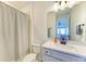 Bright bathroom features a shower with a curtain, toilet, and vanity with a large mirror and black hardware at 13071 Willow Grove Dr, Riverview, FL 33579