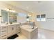 An elegant bathroom features dual vanities, a soaking tub, and large mirrors with modern lighting at 13071 Willow Grove Dr, Riverview, FL 33579