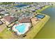 Aerial view of community amenities including a pool, clubhouse, playground, and tennis courts, all surrounded by a scenic lake at 13071 Willow Grove Dr, Riverview, FL 33579