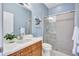 Light filled bathroom with a glass shower, wooden vanity and turtle artwork on the wall at 14727 Tudor Chase Dr, Tampa, FL 33626