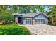 Charming blue home with stone accents, a well-manicured lawn, and a three-car garage at 14727 Tudor Chase Dr, Tampa, FL 33626
