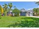 Well-maintained lawn featuring a beautiful blue home with a three-car garage, and lush landscaping at 14727 Tudor Chase Dr, Tampa, FL 33626
