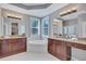 Stylish main bathroom with dual sinks, large soaking tub, wood cabinets, and tile floors at 14727 Tudor Chase Dr, Tampa, FL 33626