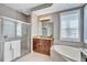 Bright bathroom featuring walk-in shower, large soaking tub, wood cabinets, and tile floors at 14727 Tudor Chase Dr, Tampa, FL 33626