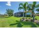 Lush backyard featuring a screened lanai, tropical plants, and views of a tranquil lake at 16139 Coquina Bay Ln, Wimauma, FL 33598