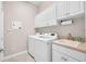 Bright laundry room featuring modern washer and dryer units, white cabinets, and a utility sink at 16139 Coquina Bay Ln, Wimauma, FL 33598
