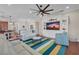 Open living room with built-in shelving, television, ceiling fan, and colorful striped rug at 16139 Coquina Bay Ln, Wimauma, FL 33598