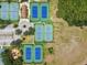 Overhead view of multiple tennis courts with vibrant blue surfaces and green surrounds at 16910 Equestrian Trl, Odessa, FL 33556